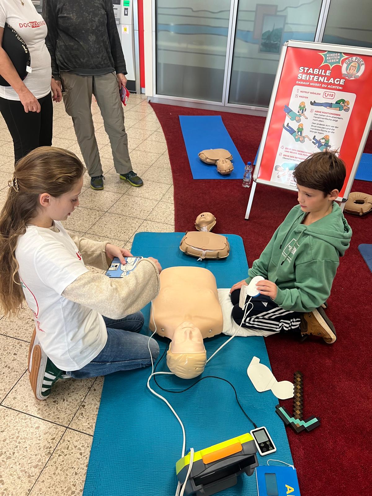 Kinder üben mit Trainingspuppe und AED