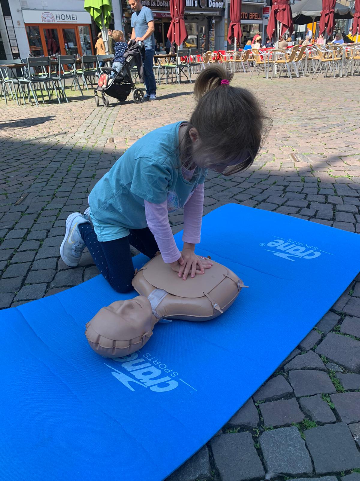 Kind übt Herzdruckmassage draußen